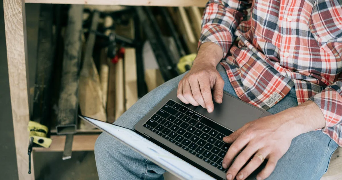 Contractor reviewing website costs on a laptop at a workbench